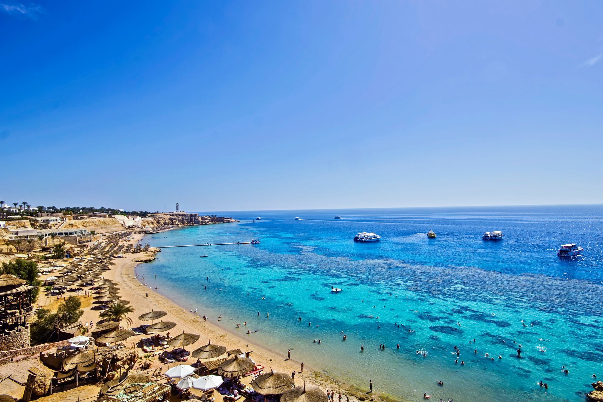 Egypt An aerial view of a beach with people swimming in the ocean.