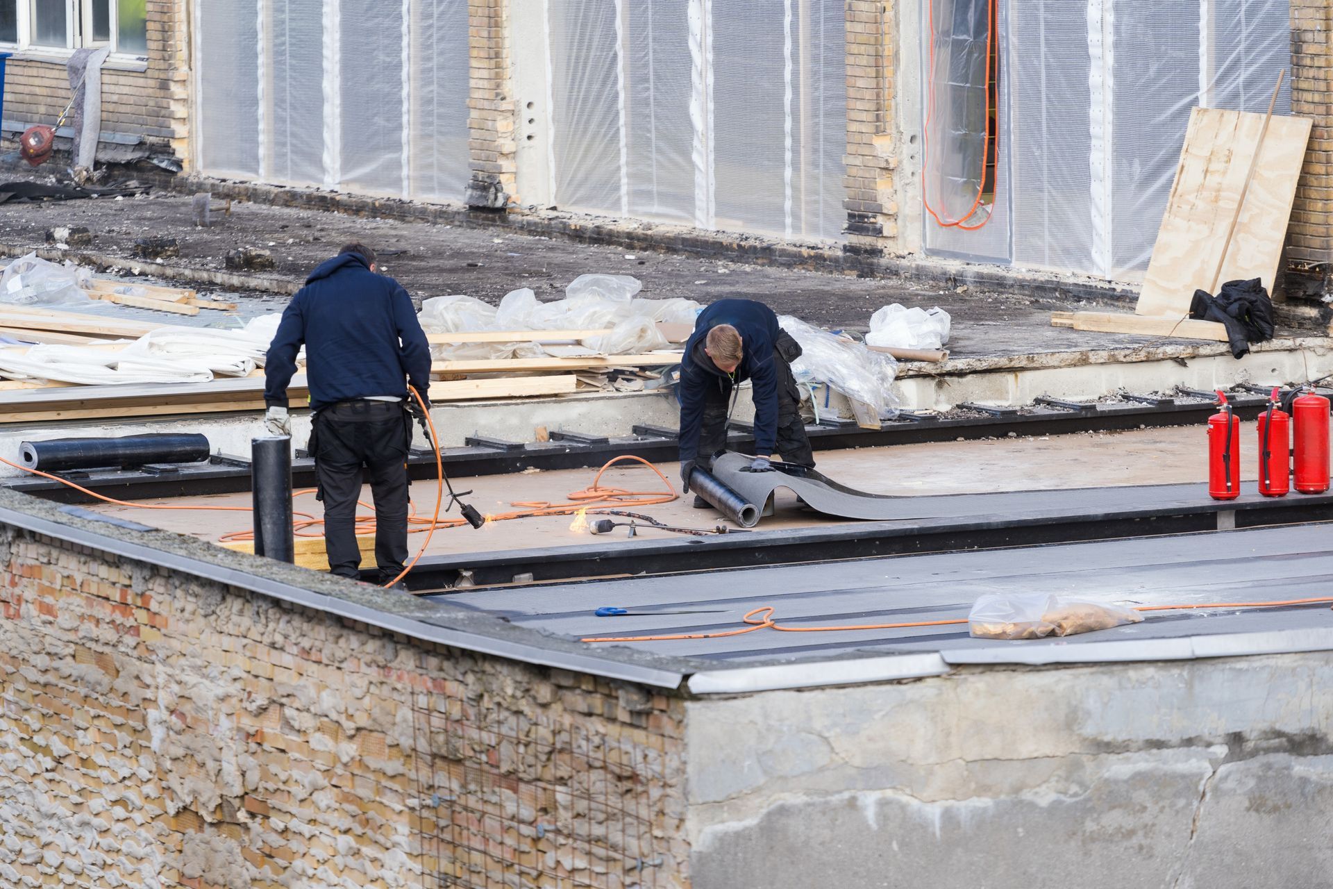 Crew performing residential flat rubber roof installation on low-slope residential building.