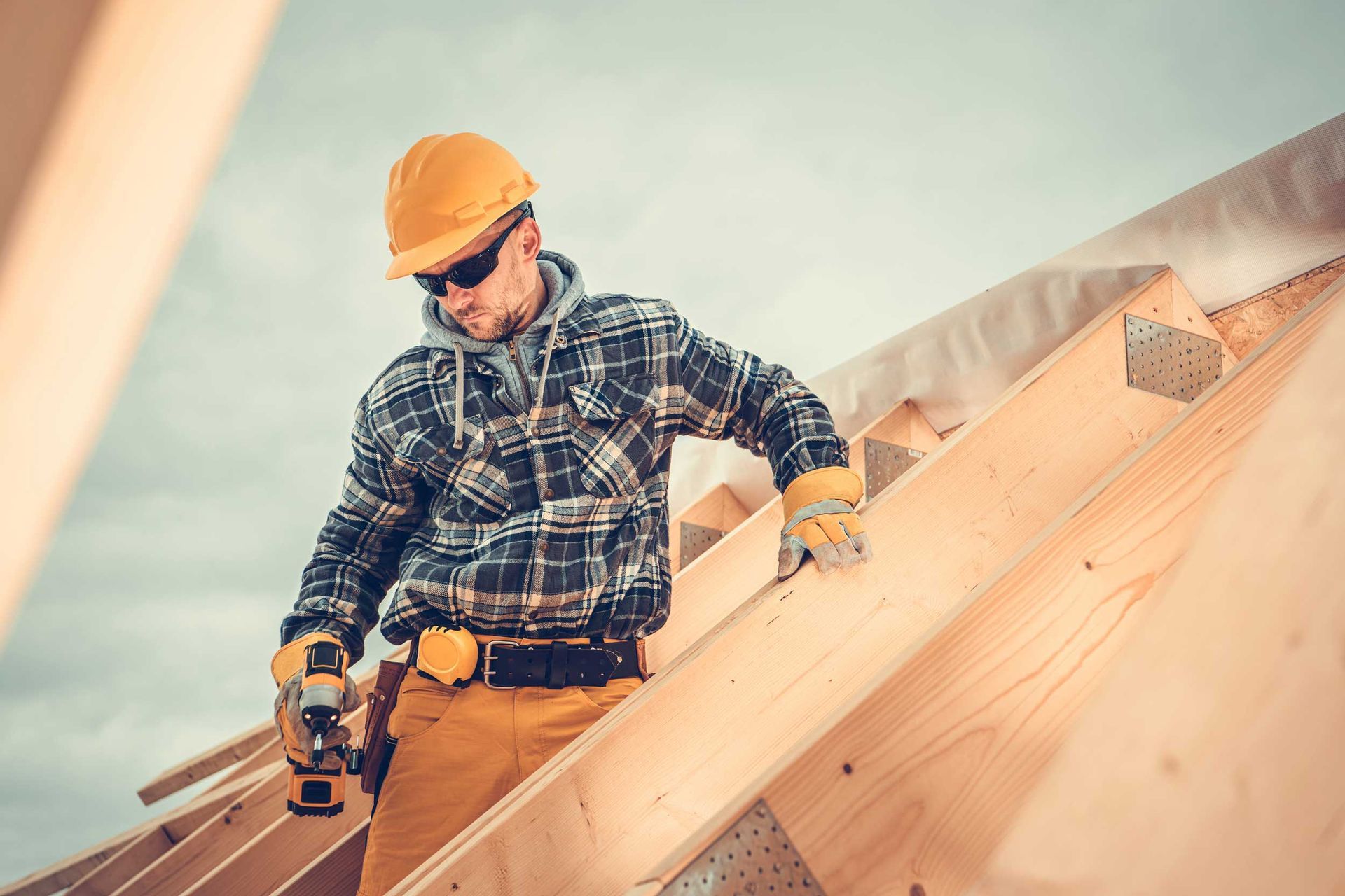 Residential roof company contractor in a hard hat installing wood roof framing on a new home.