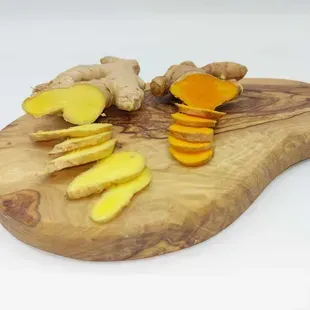 Racine de curcuma tranchée sur une planche à découper en bois, montrant sa chair jaune-orange vif