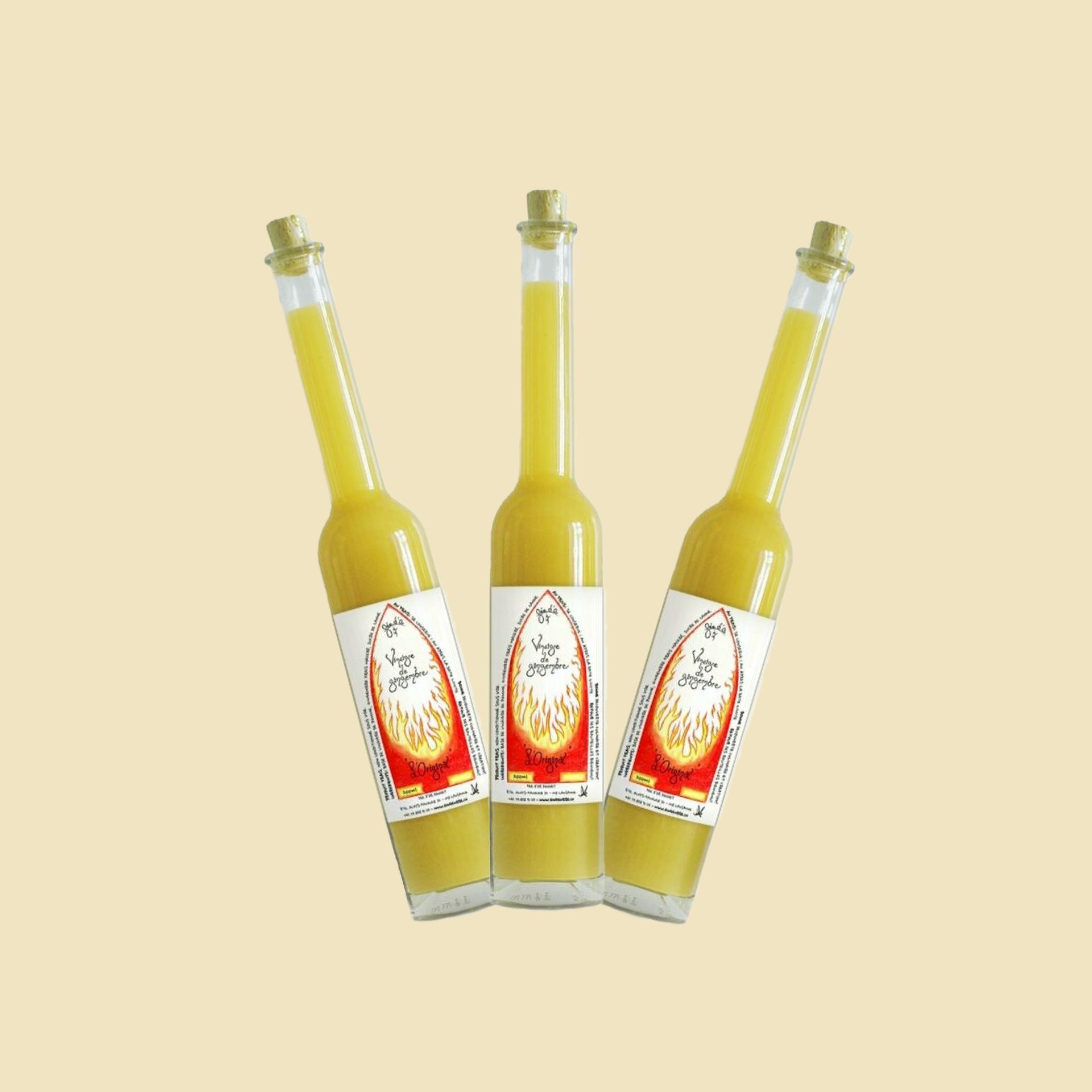 Trois bouteilles jaunes à étiquettes rouges et blanches, dressées sur un fond beige.