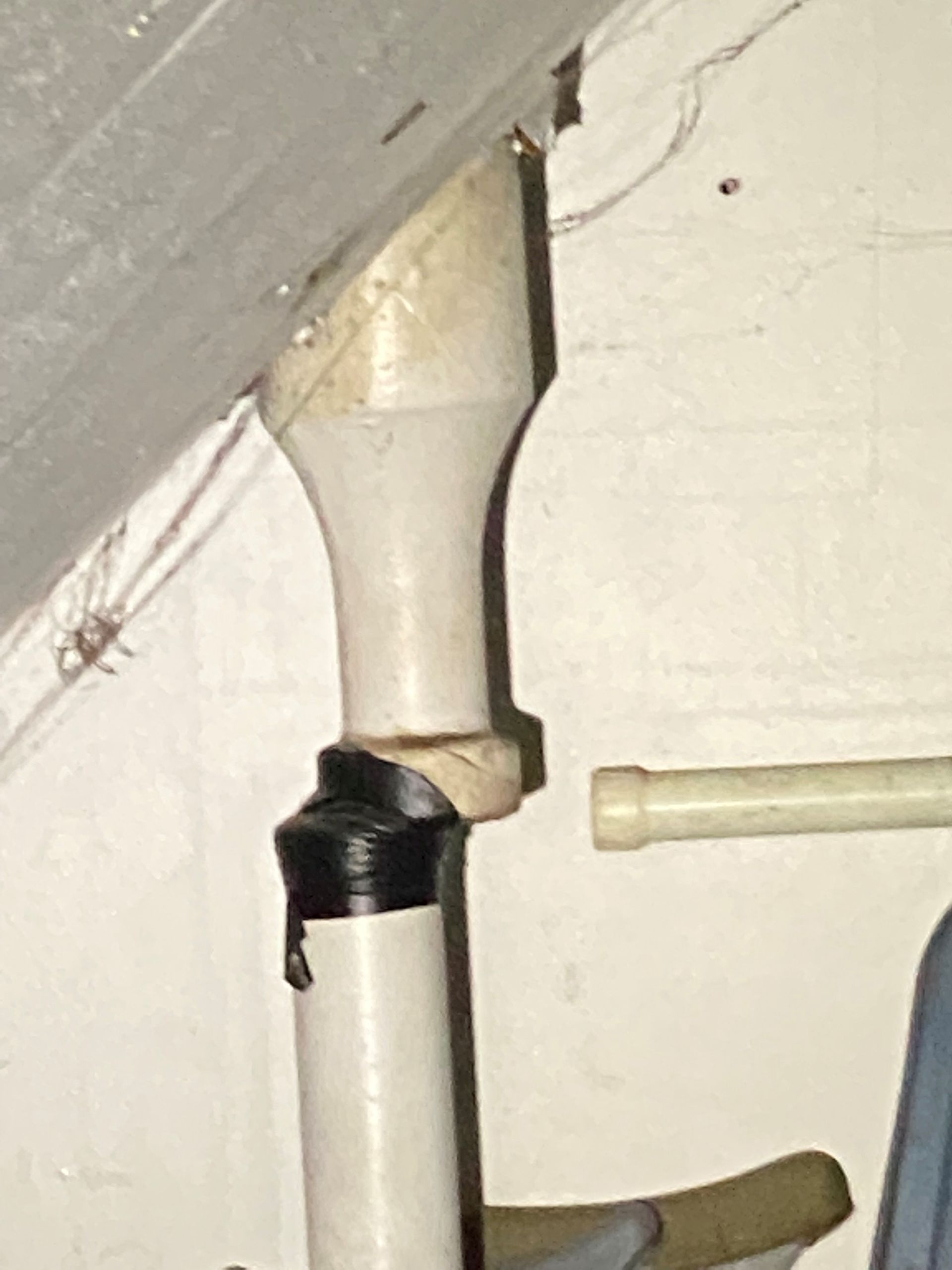 A pipe connection with a visible gap, taped with black electrical tape, against a wall near a sloped surface.