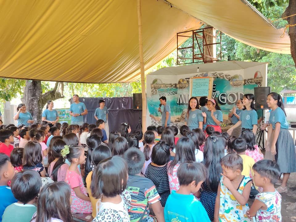 A large group of people are sitting under a tent.