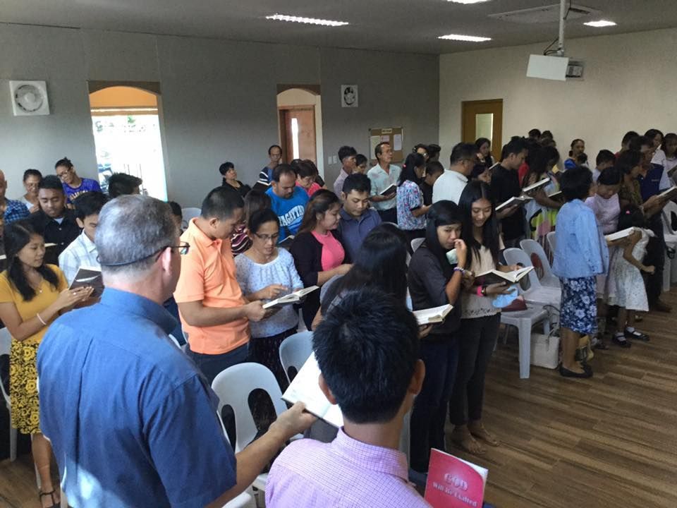 A large group of people are singing together in a room.
