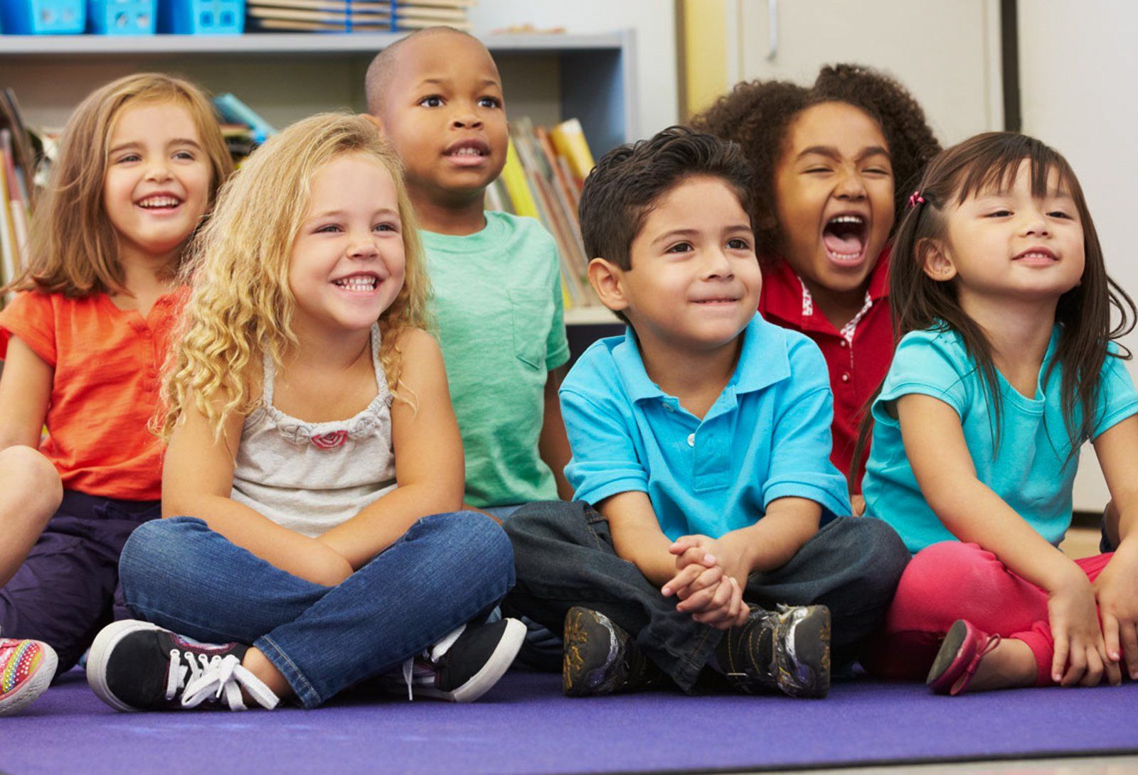 Eine Gruppe Kinder sitzt in einem Klassenzimmer auf dem Boden.