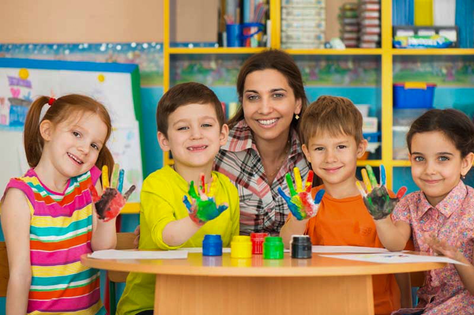 Eine Gruppe Kinder sitzt mit bemalten Händen an einem Tisch.