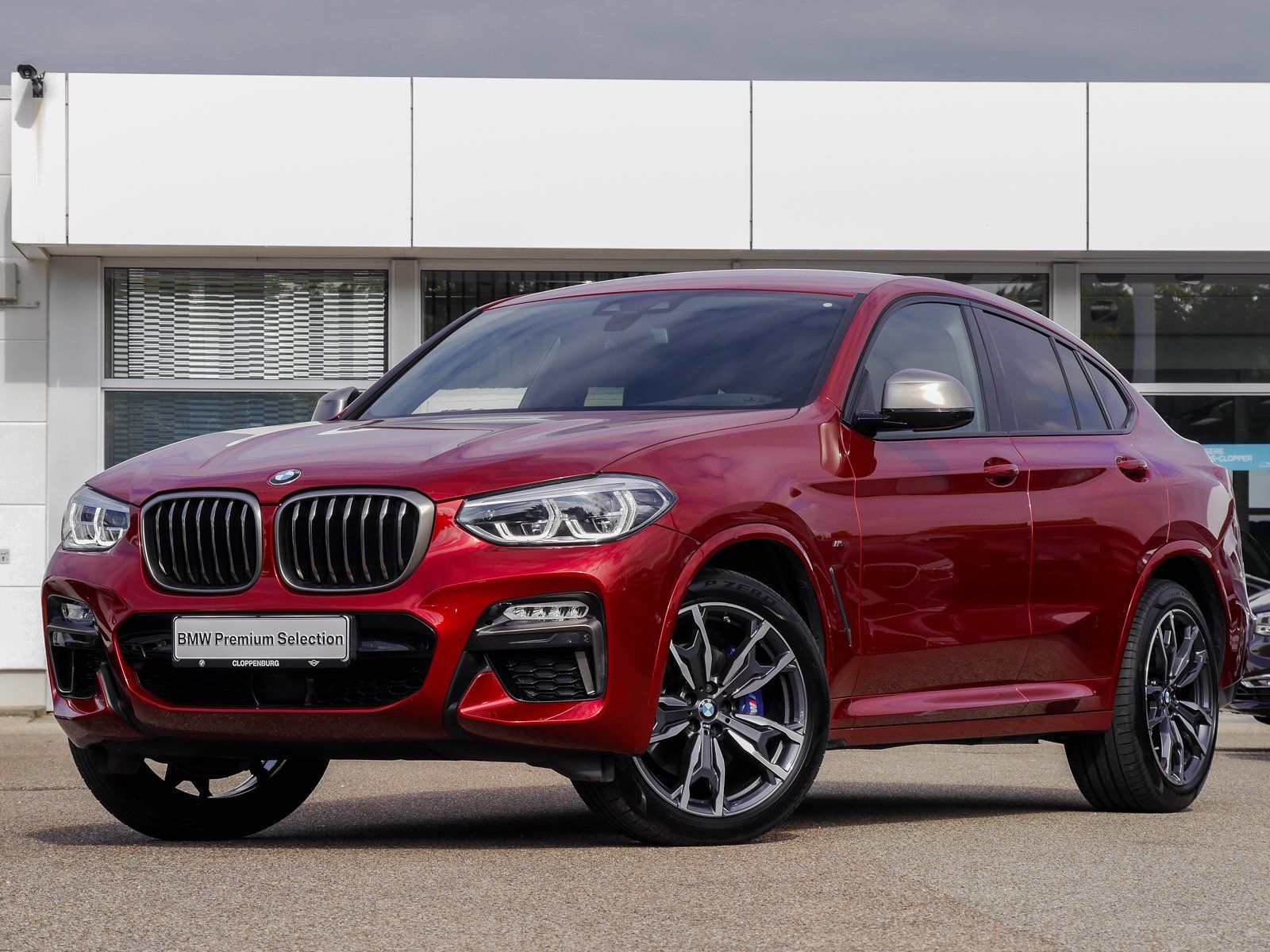 Vor einem Gebäude parkt ein roter BMW X4.