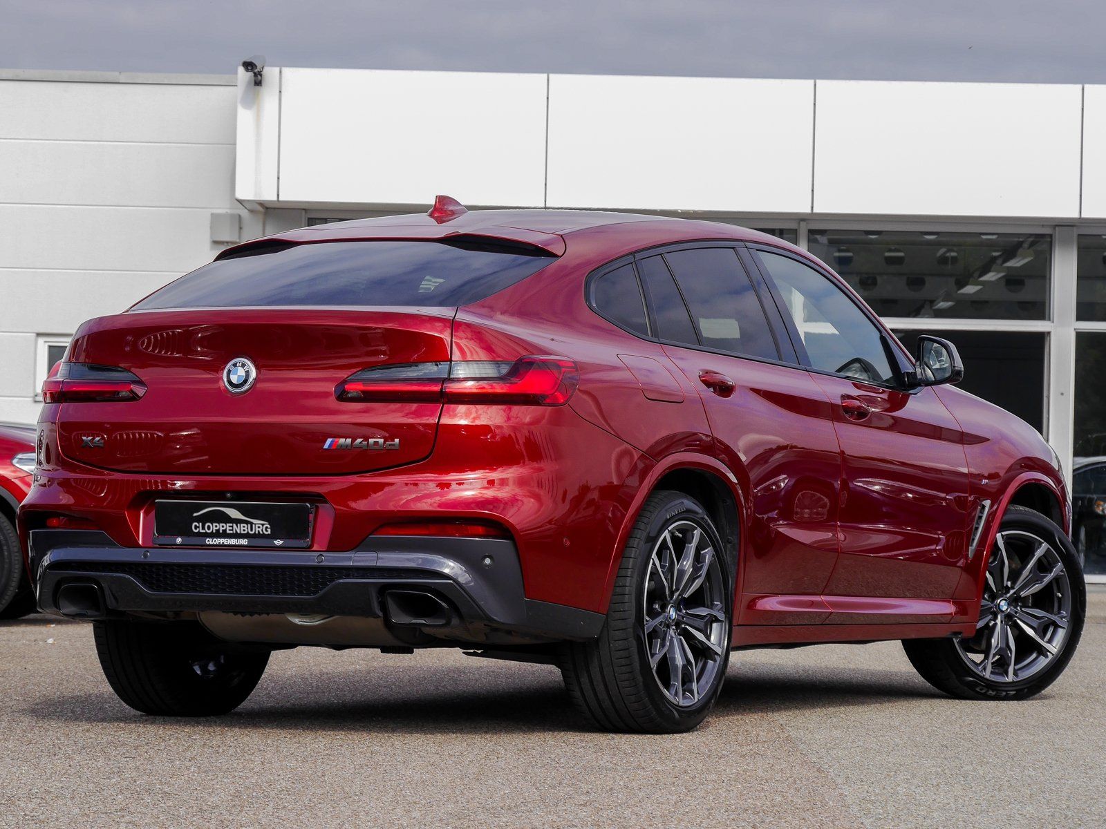 Vor einem Gebäude parkt ein roter BMW X4.