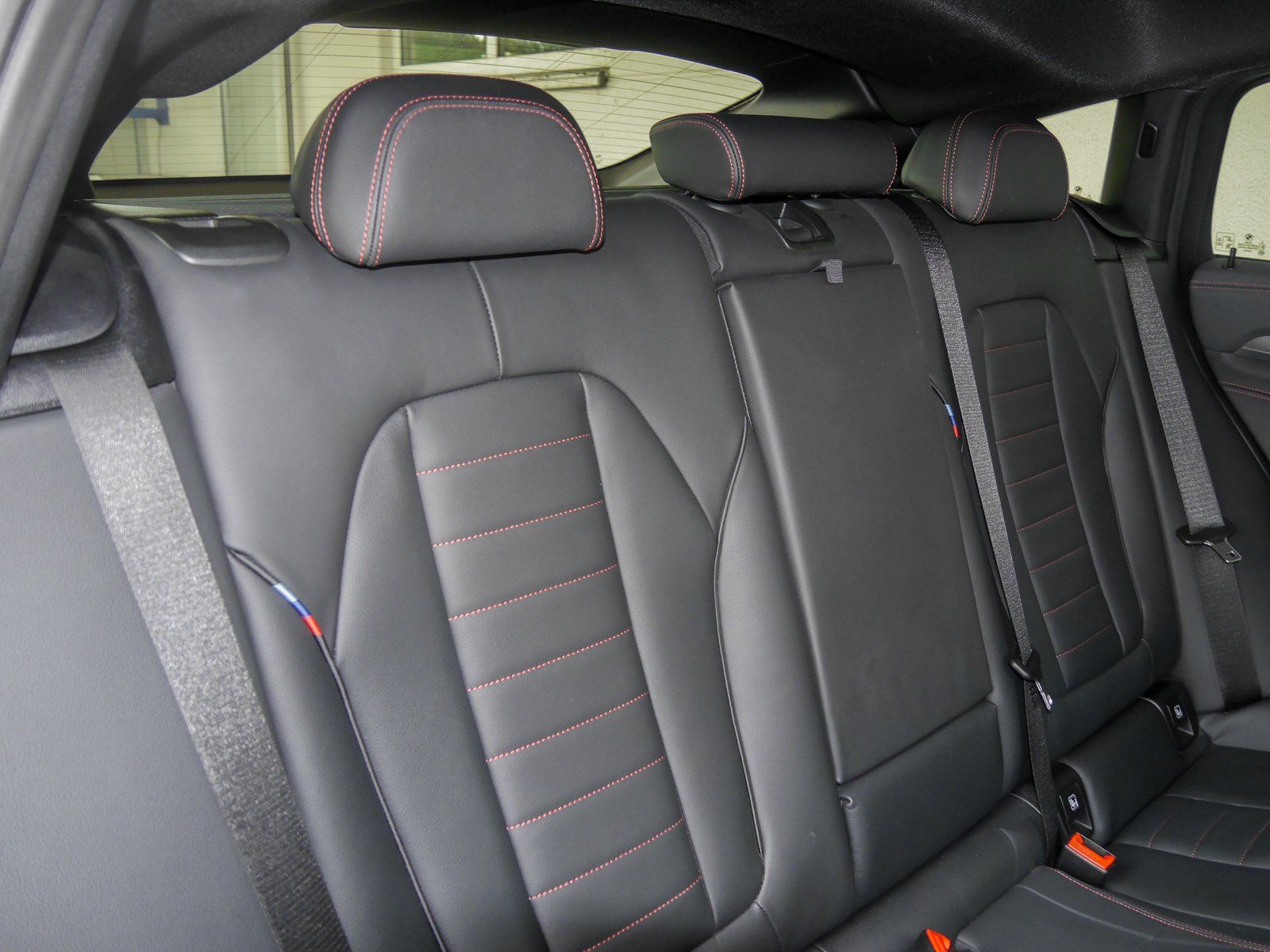 Die Rückbank eines Autos mit Sicherheitsgurten und Kopfstützen.