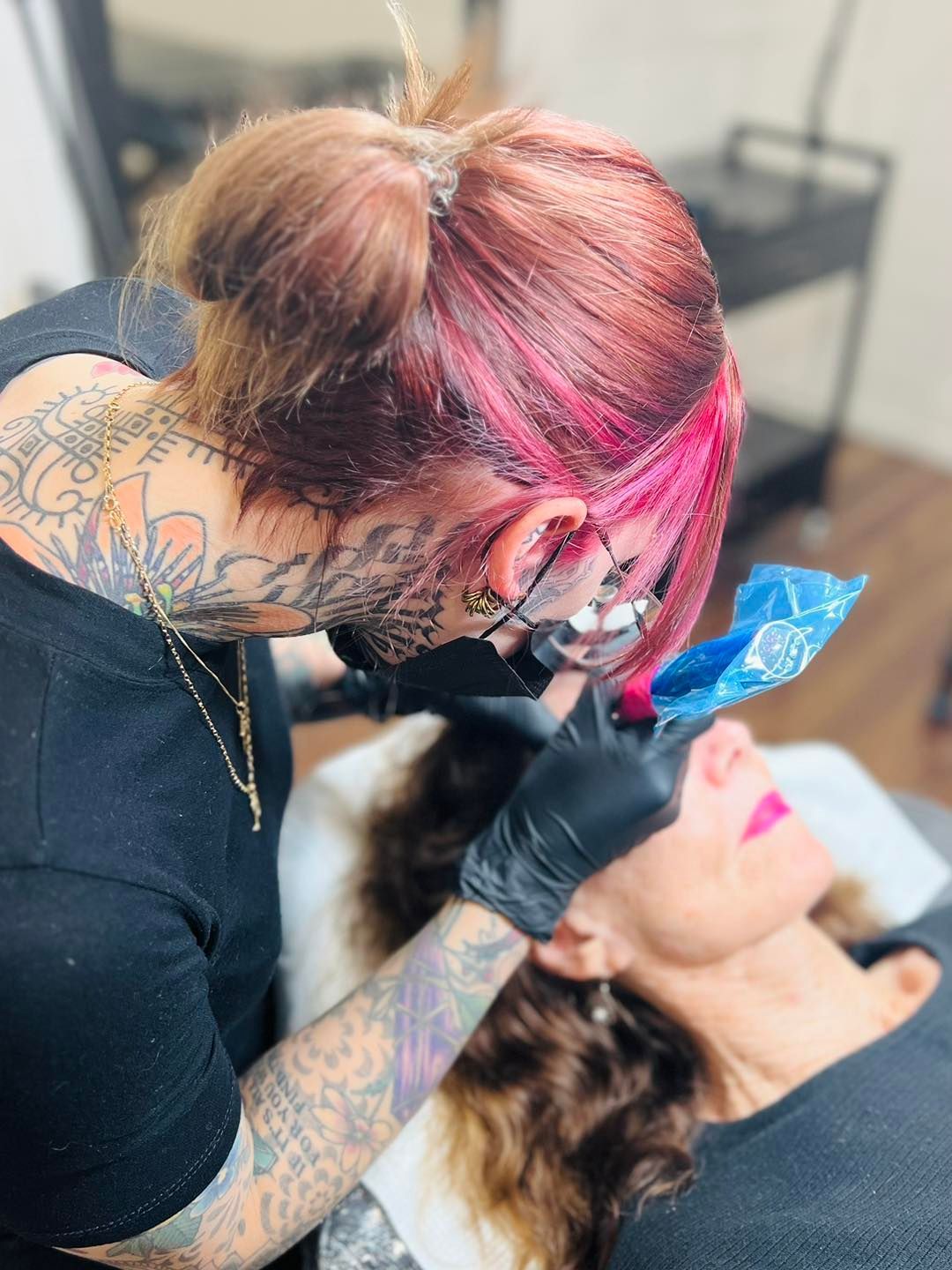 Tattoo Artist With Colorful Hair Works on Client's Eyebrow — Artisan Cosmetic Tattoo & Beauty in Worongary, QLD