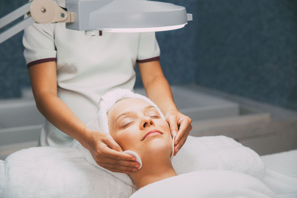 Person Receiving Facial Treatment in Spa, Therapist Using Cotton Pads — Artisan Cosmetic Tattoo & Beauty in Worongary, QLD