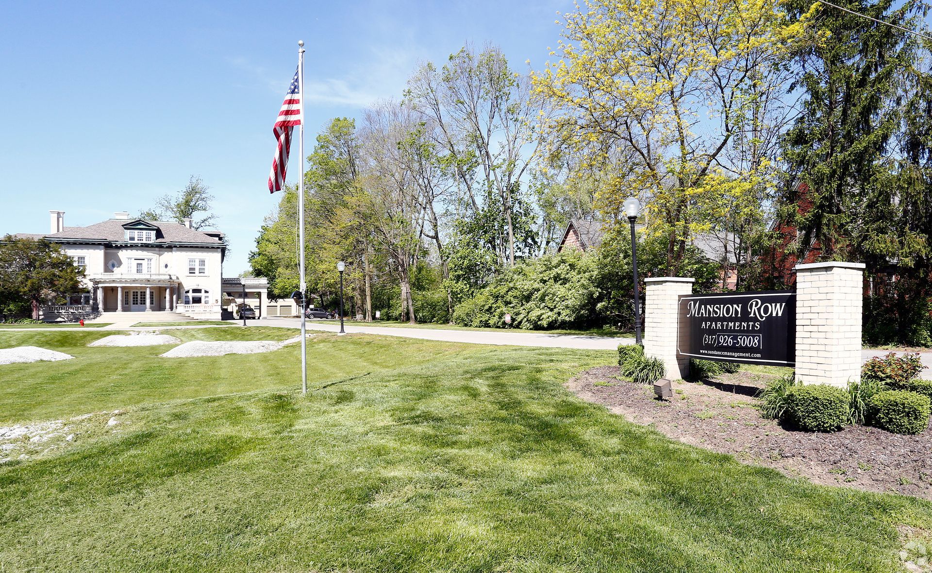 An american flag is flying in front of a large house.