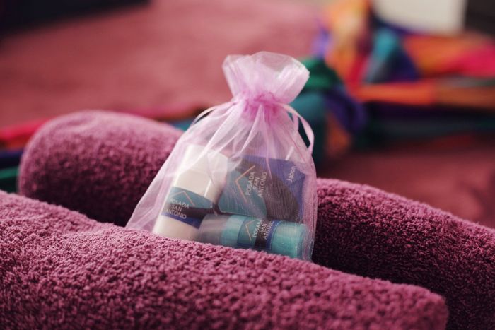 Bolsa de regalo transparente con pequeños artículos envueltos sobre una toalla morada