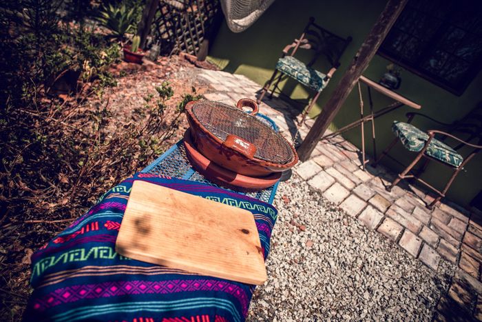 Puesto de mercado al aire libre con coloridos textiles tejidos, una tabla de madera y una cesta en un camino empedrado.