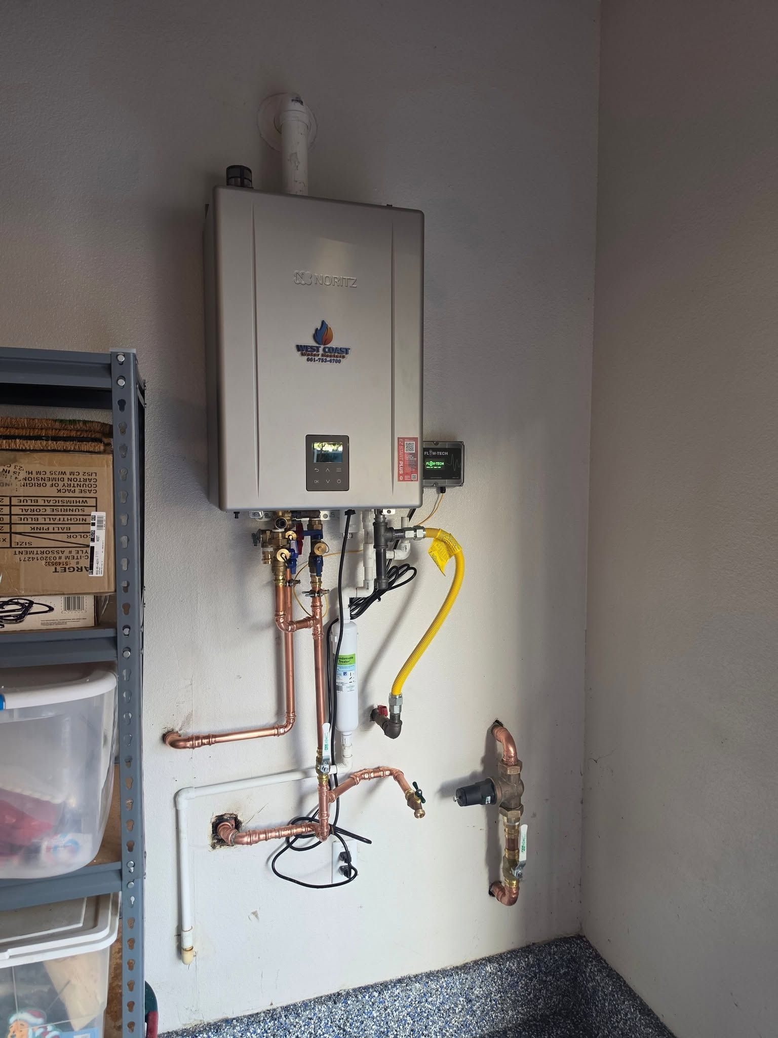 Wall-mounted tankless water heater with exposed pipes and valves in a utility room