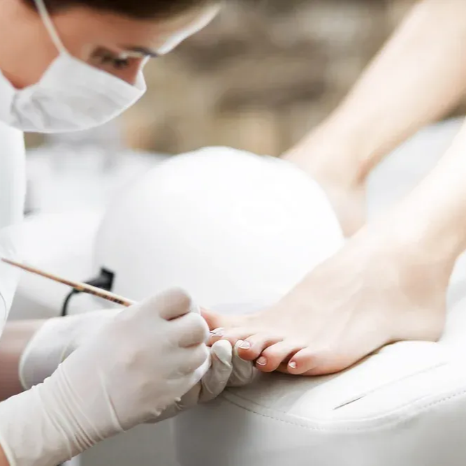 Podologe schneidet Zehennägel mit einer Nagelschere während einer Fußpflegebehandlung