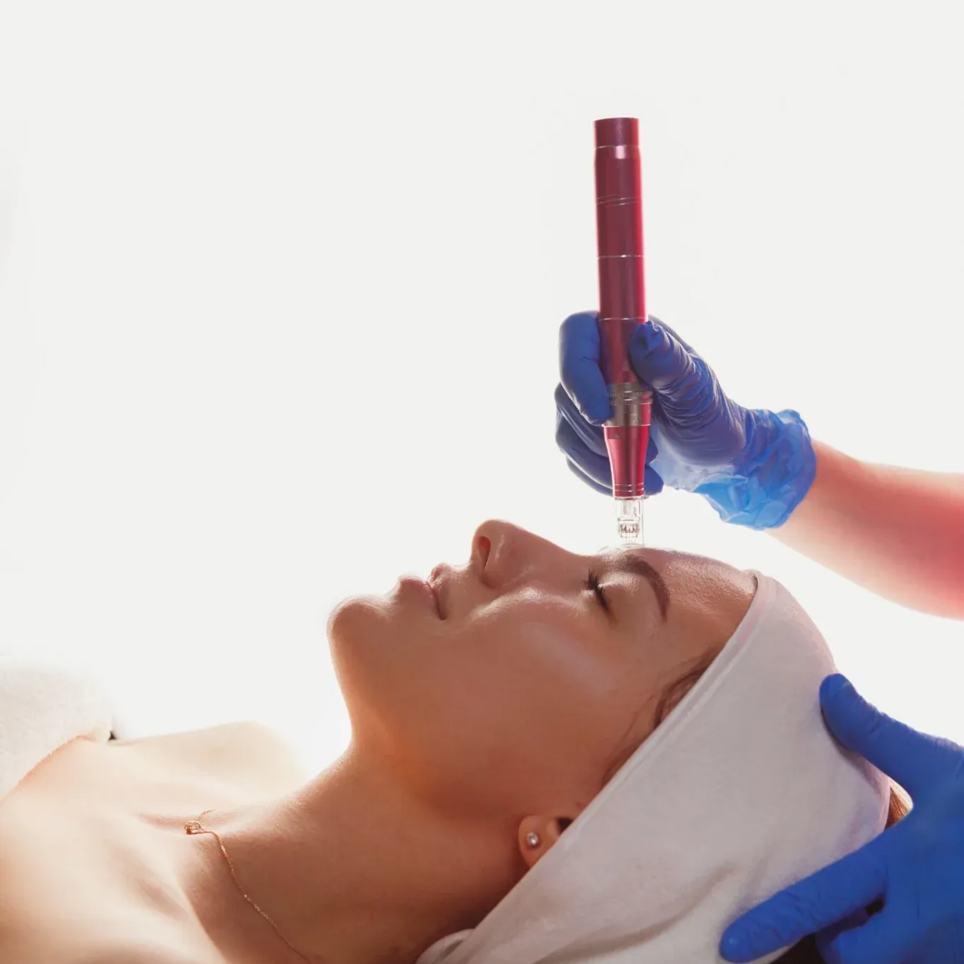 Behandschuhte Hände wenden ein rotes Gesichtsbehandlungsgerät an einer Frau an, die auf einer Spa-Liege liegt.