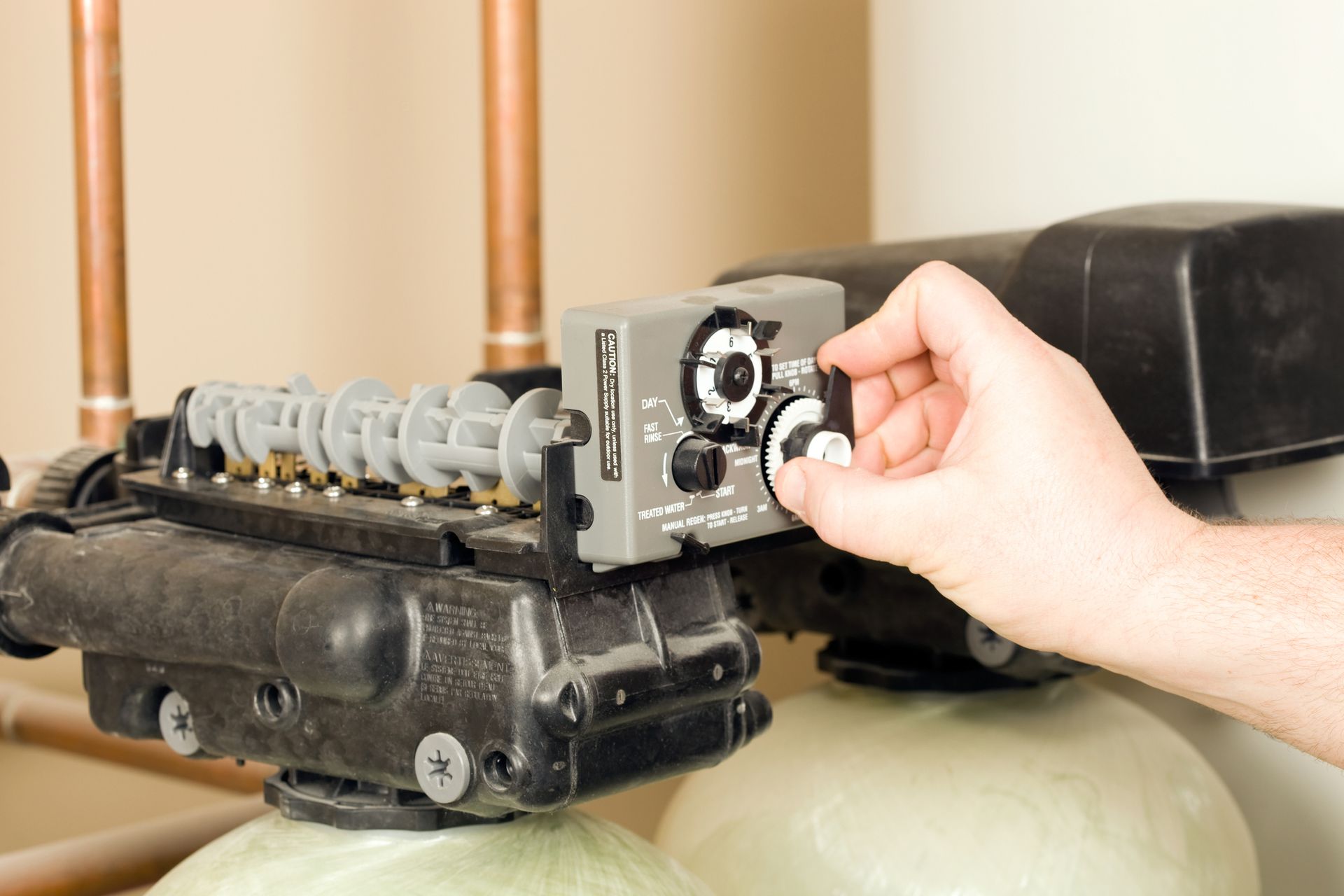 A person is adjusting a valve on a water softener. A person is adjusting a valve on a water softener.