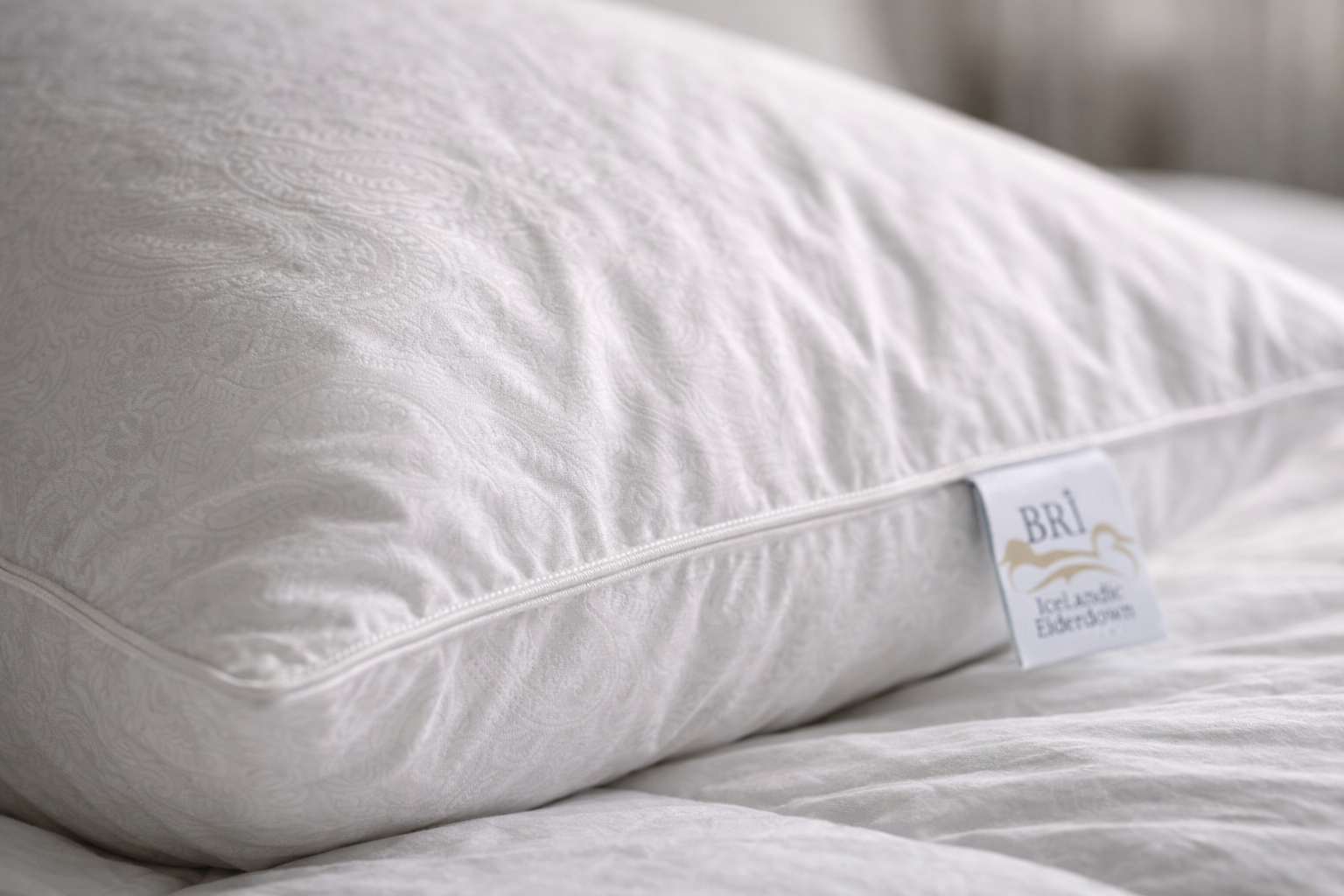 Sleeping baby tucked in white eiderdown bedding on a bed in a softly lit bedroom