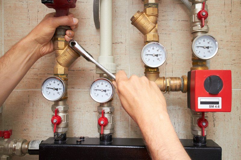 Hands Tightening a Valve on a Network of Pipes and Gauges — Tony Brown Plumbing & Gas Services in South Grafton, NSW
