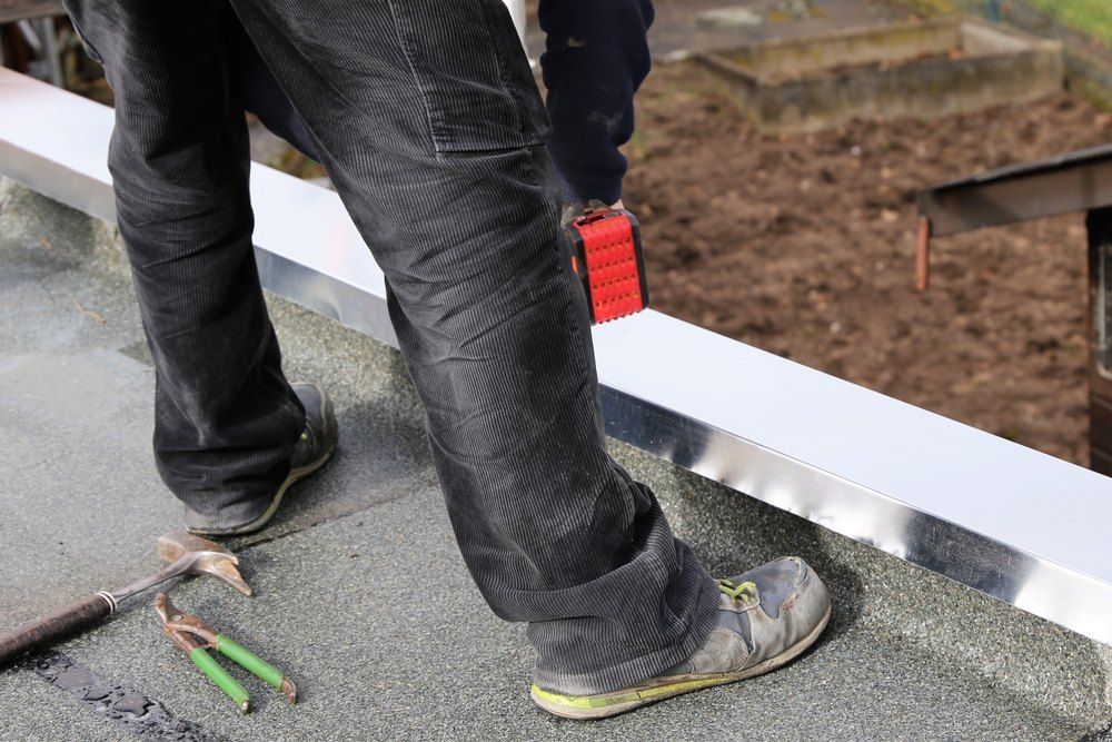 A Man is Standing on a Roof With a Hammer and Pliers — Tony Brown Plumbing & Gas Services in South Grafton, NSW