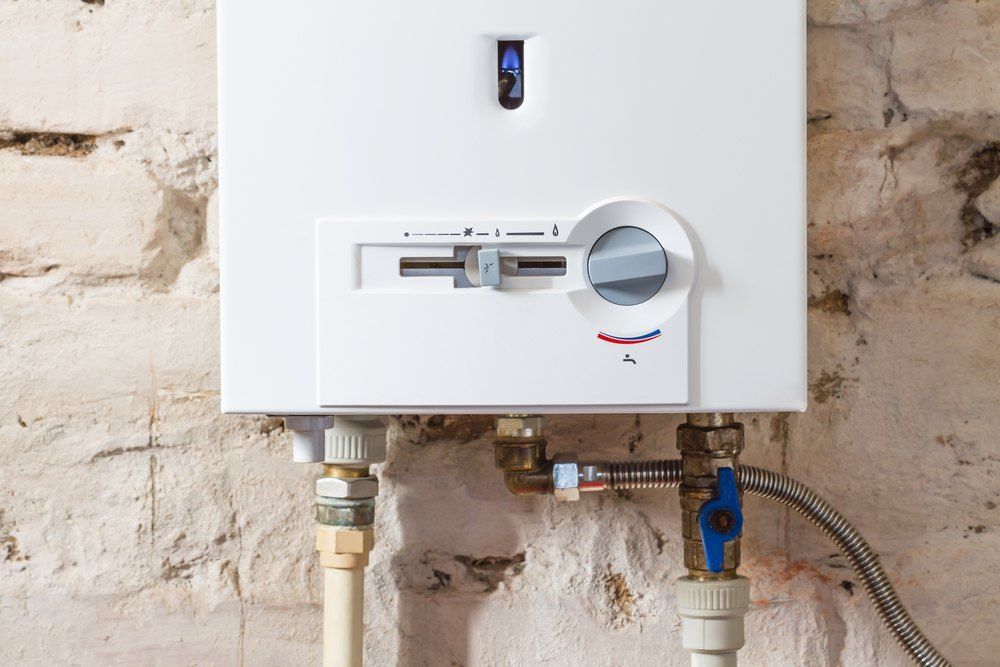 A White Water Heater is Attached to a Brick Wall — Tony Brown Plumbing & Gas Services in South Grafton, NSW
