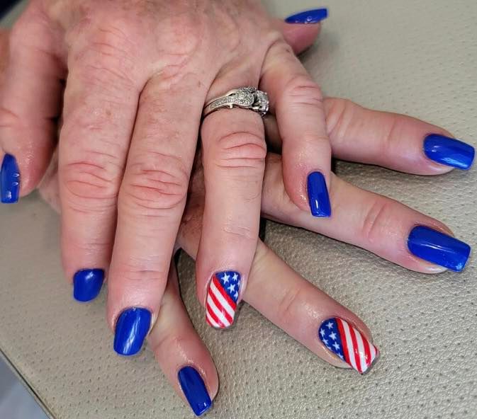 A woman 's nails are painted blue and red with an american flag design.