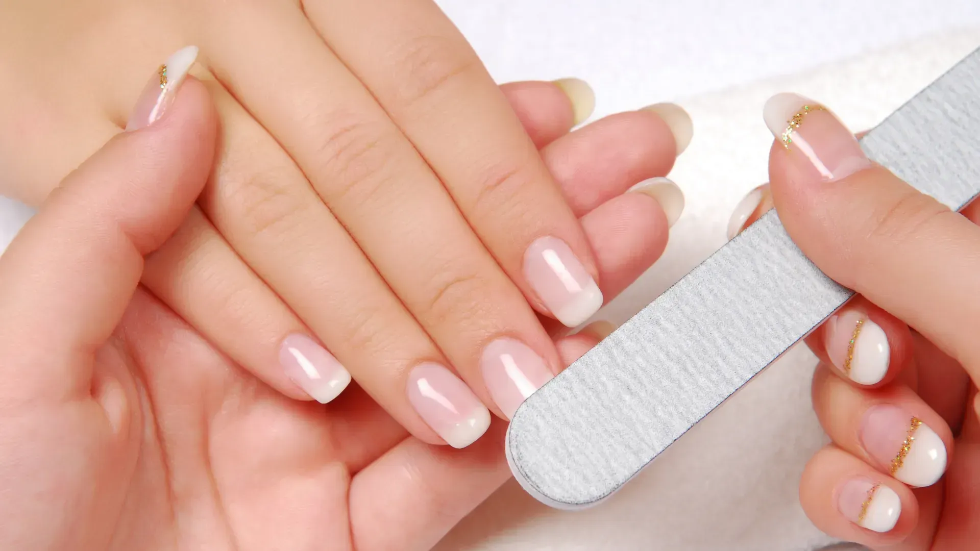 A woman is getting her nails done by a nail file.
