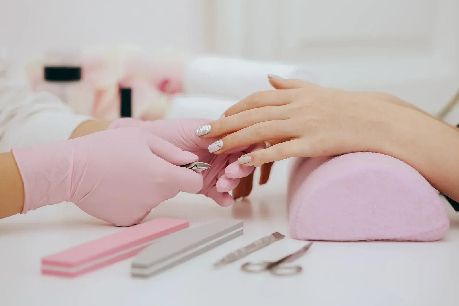 A woman is getting her nails done by a nail artist in a salon.