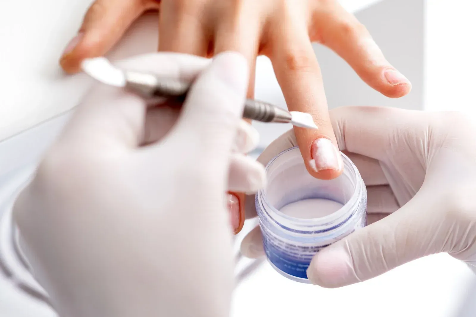 A person is applying acrylic powder to a woman 's nails.