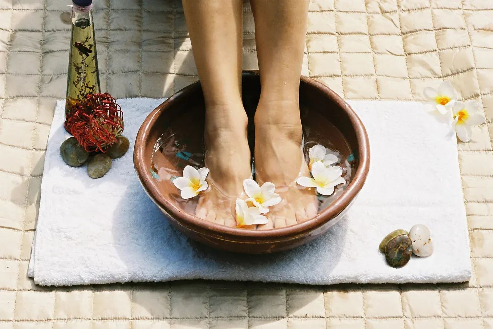 A woman 's feet are in a bowl of water with flowers