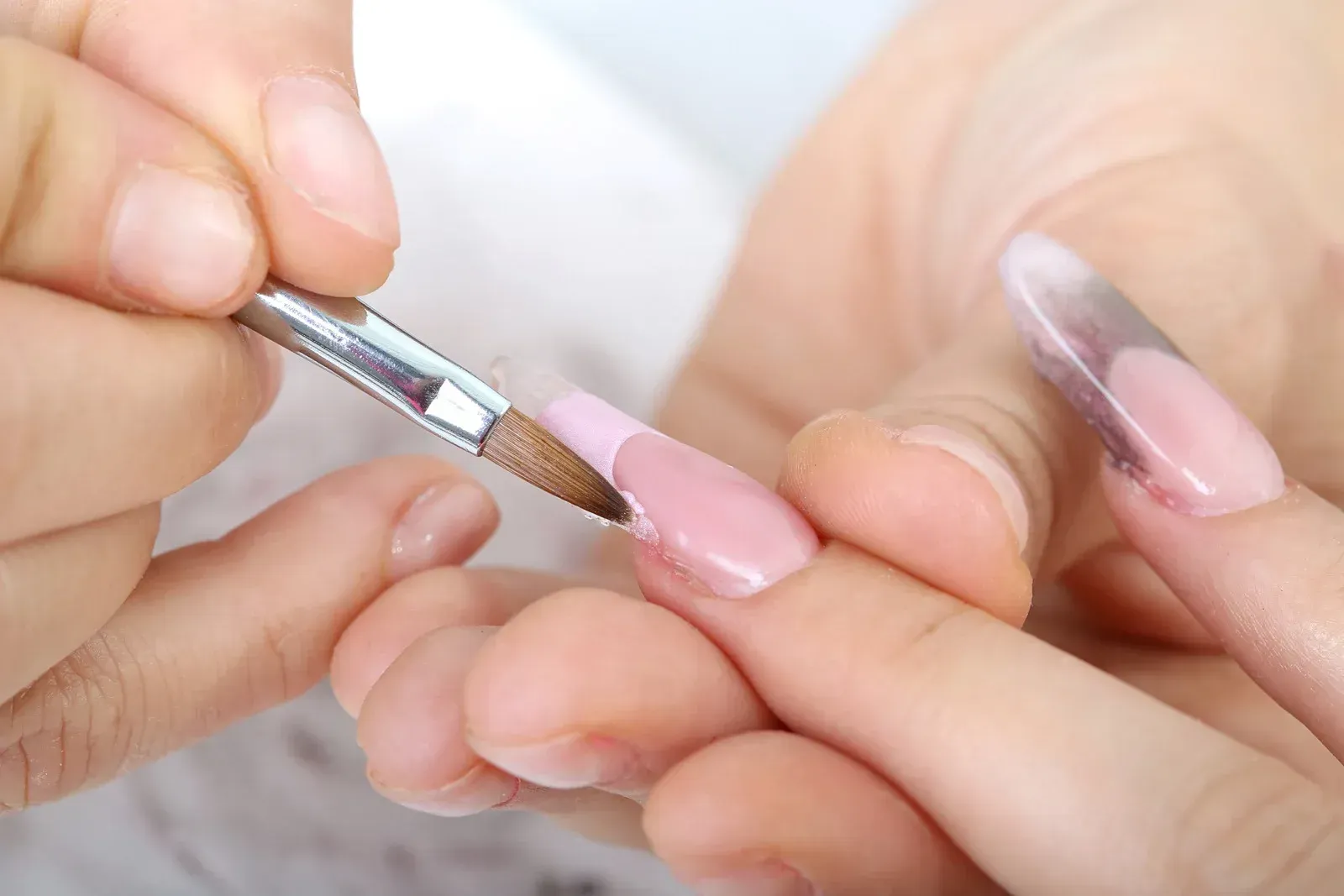 A woman is getting her nails painted with a brush.