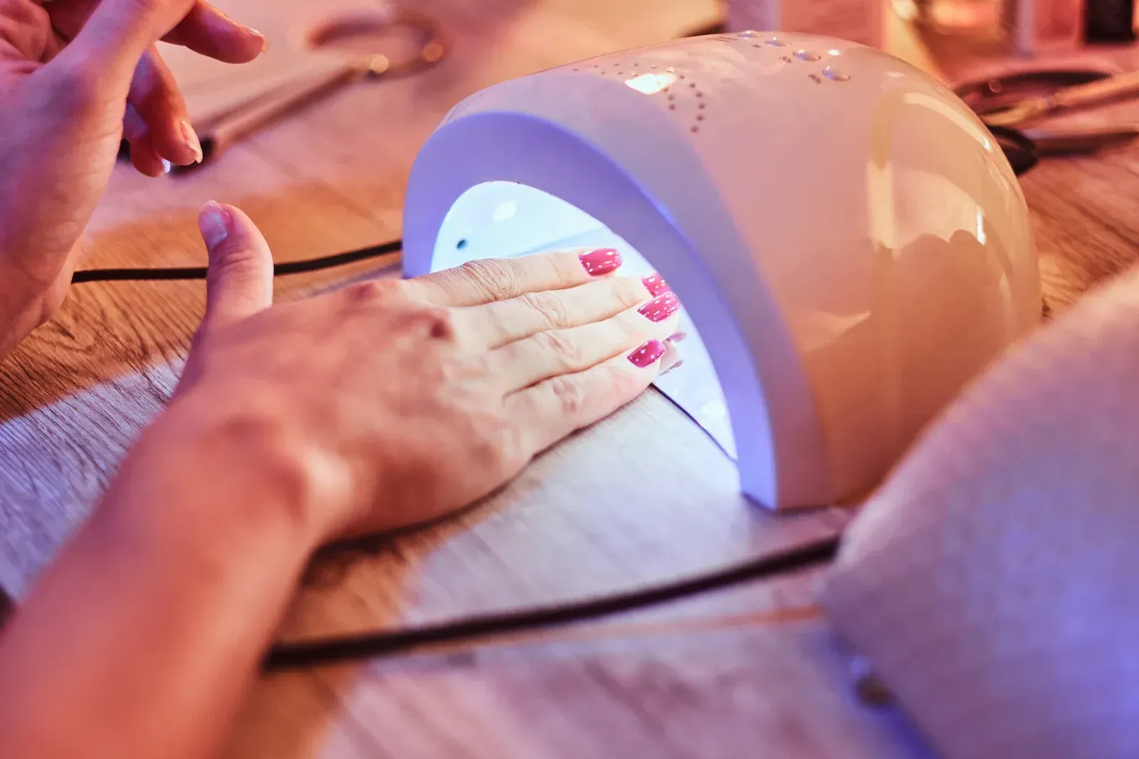 A woman is getting her nails done in a nail lamp.