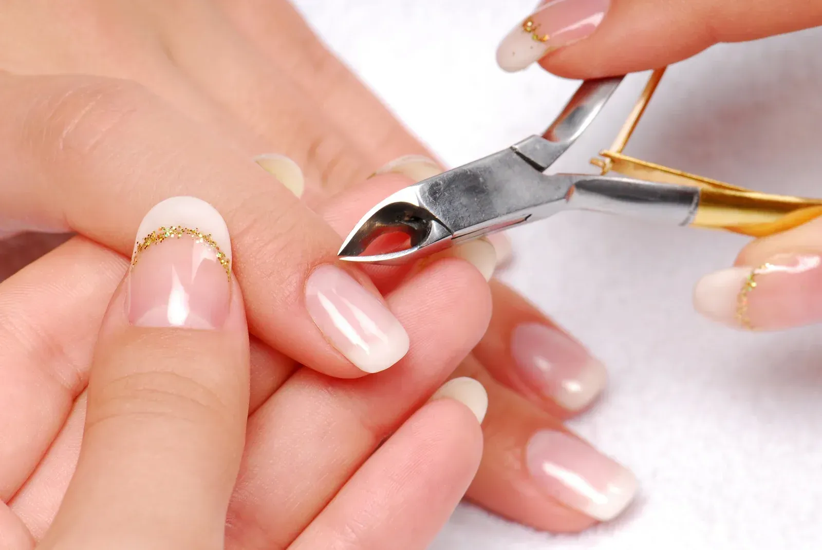 A woman is getting her nails cut with a pair of scissors