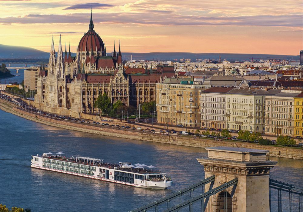 A cruise ship is floating on a river in front of a city.