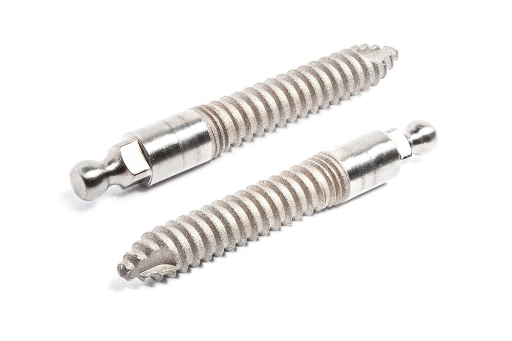 Two stainless steel screws are sitting next to each other on a white surface.