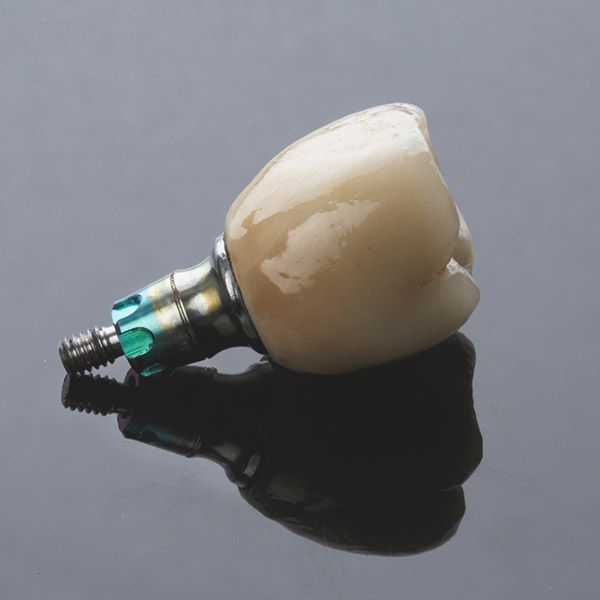A dental implant is laying on a black surface.