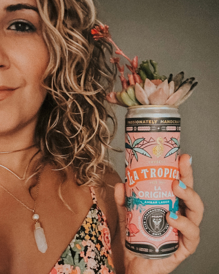 Woman holding a colorful tropical-themed can beside her face