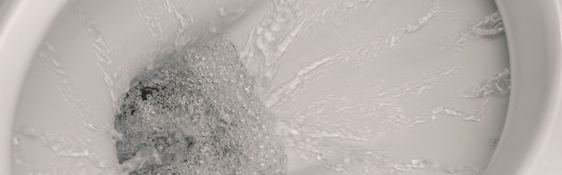A close up of a toilet with water coming out of it.