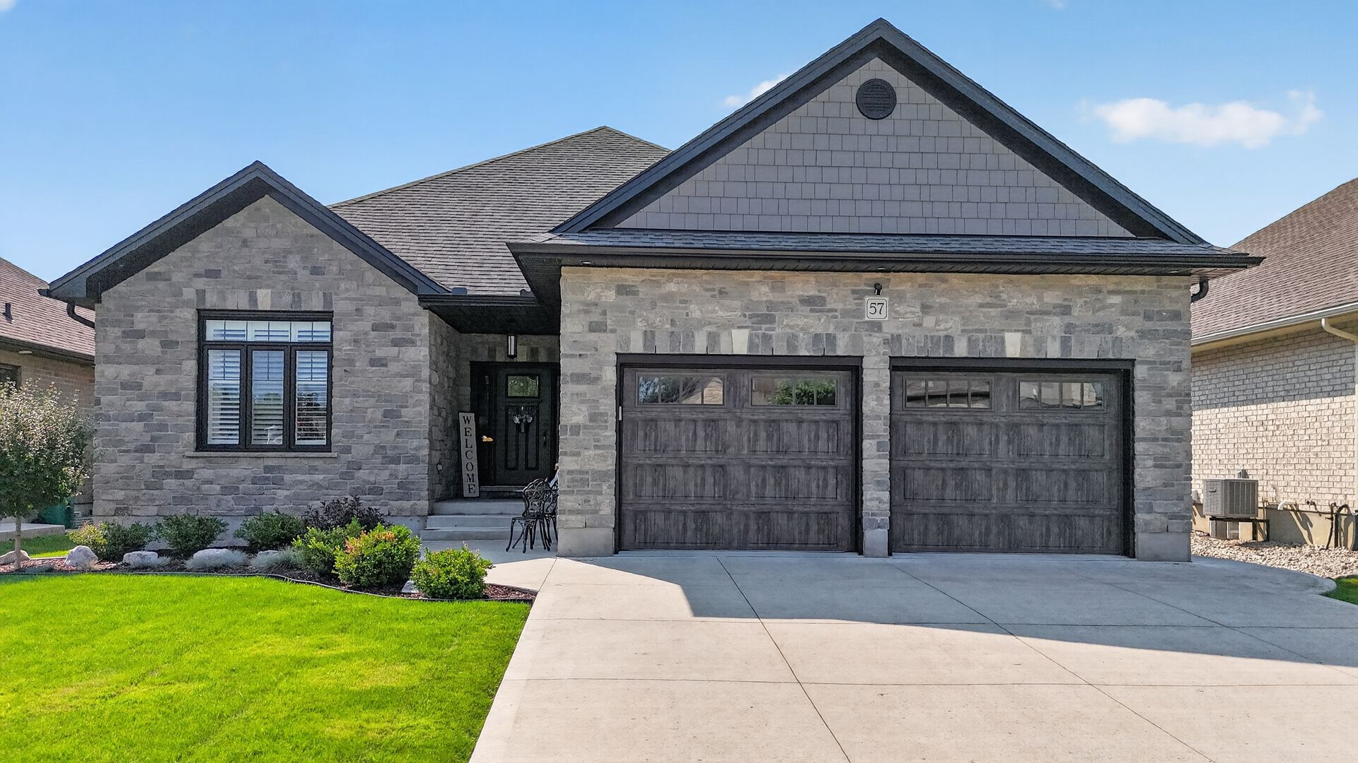 Stone bungalow front exterior with double garage and landscaped garden