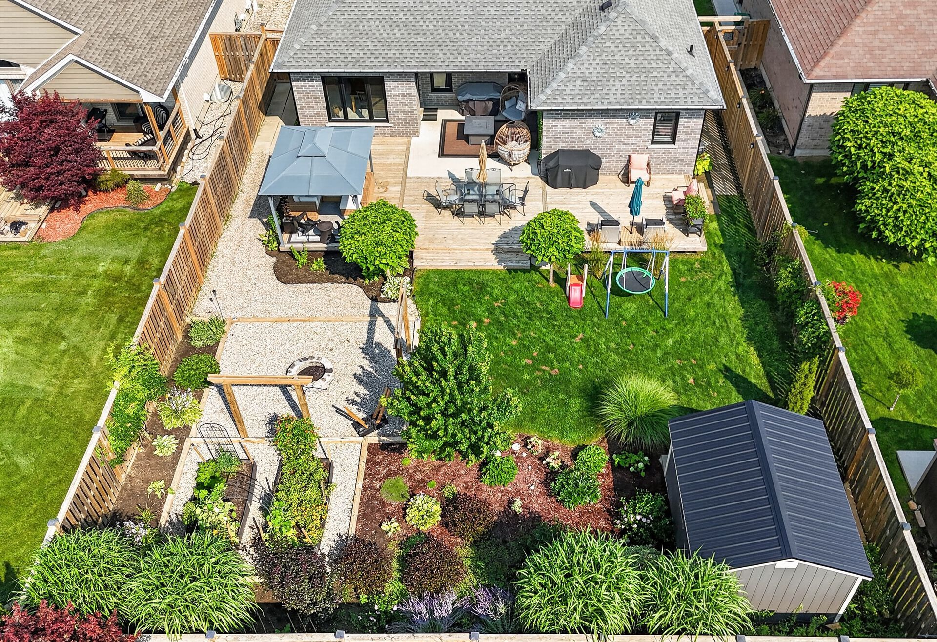 Aerial drone photograph of backyard with pergola, garden beds, patio and lawn