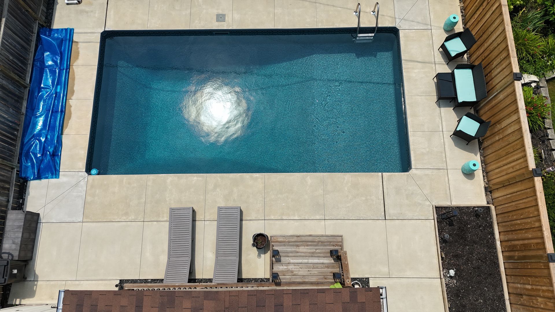Top-down drone photograph of rectangular swimming pool with patio and lounge chairs