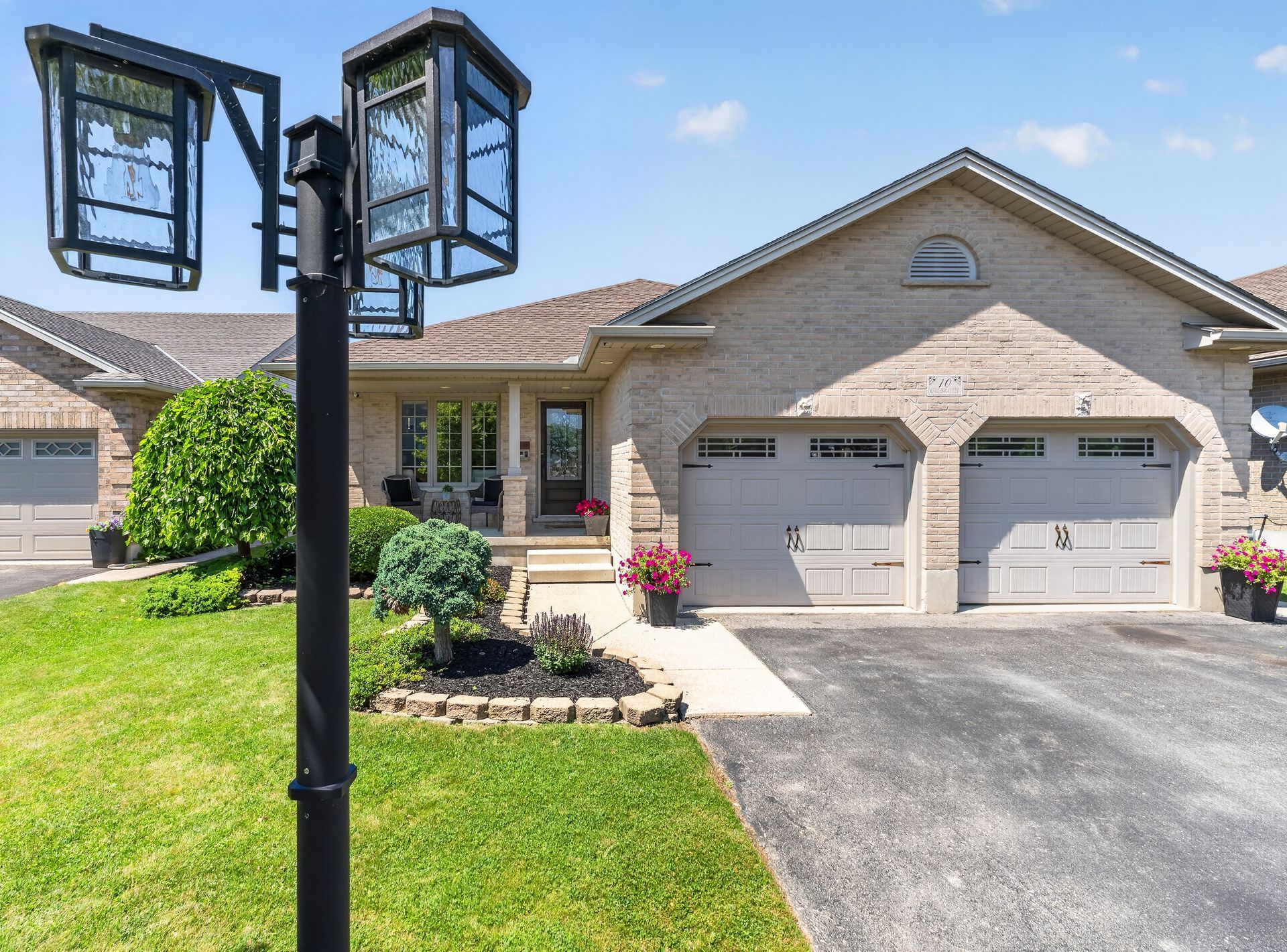 Bungalow front exterior with double garage, lamp post and flower beds