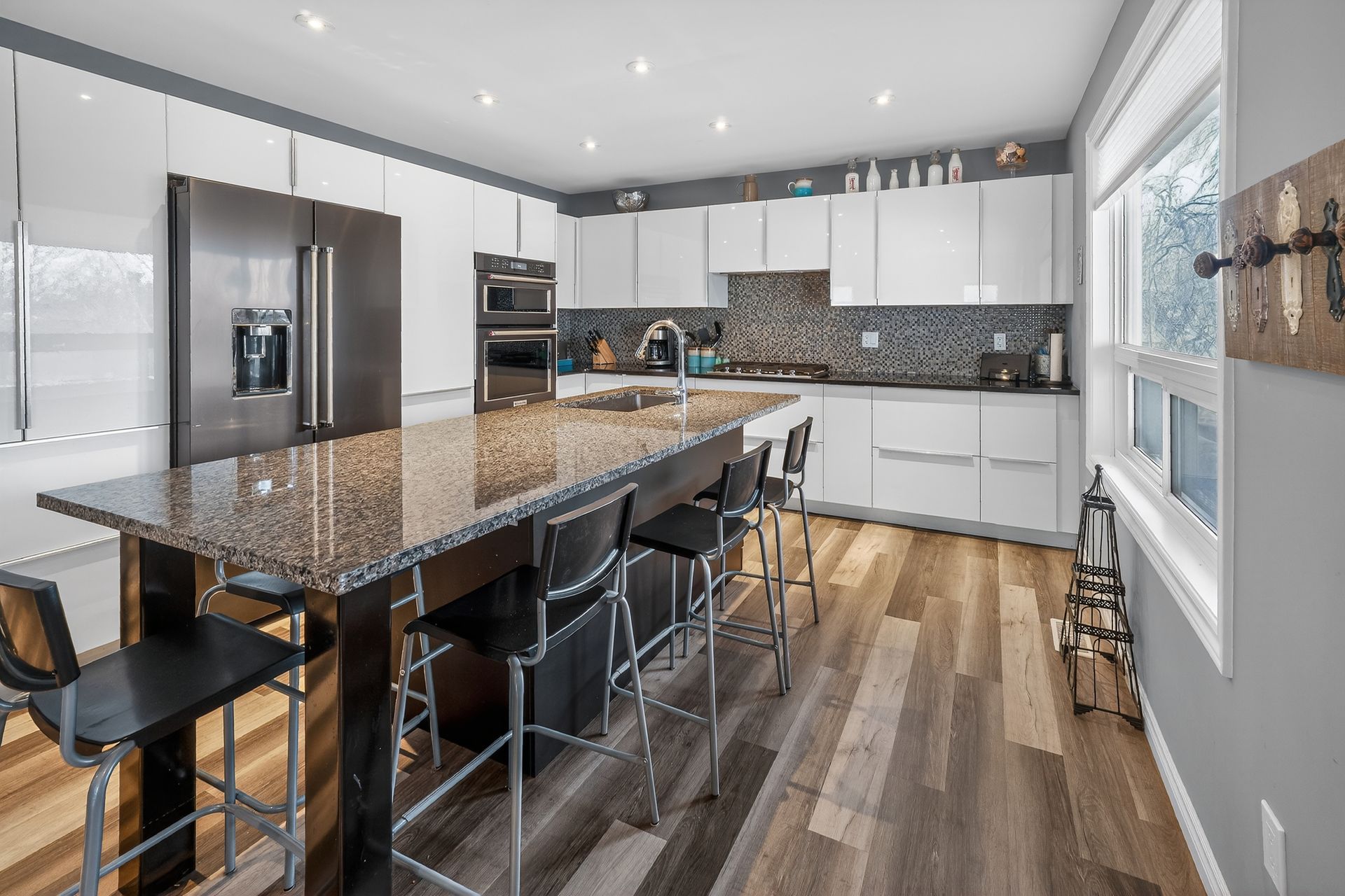 Modern white kitchen with large island, mosaic tile backsplash and stainless steel appliances