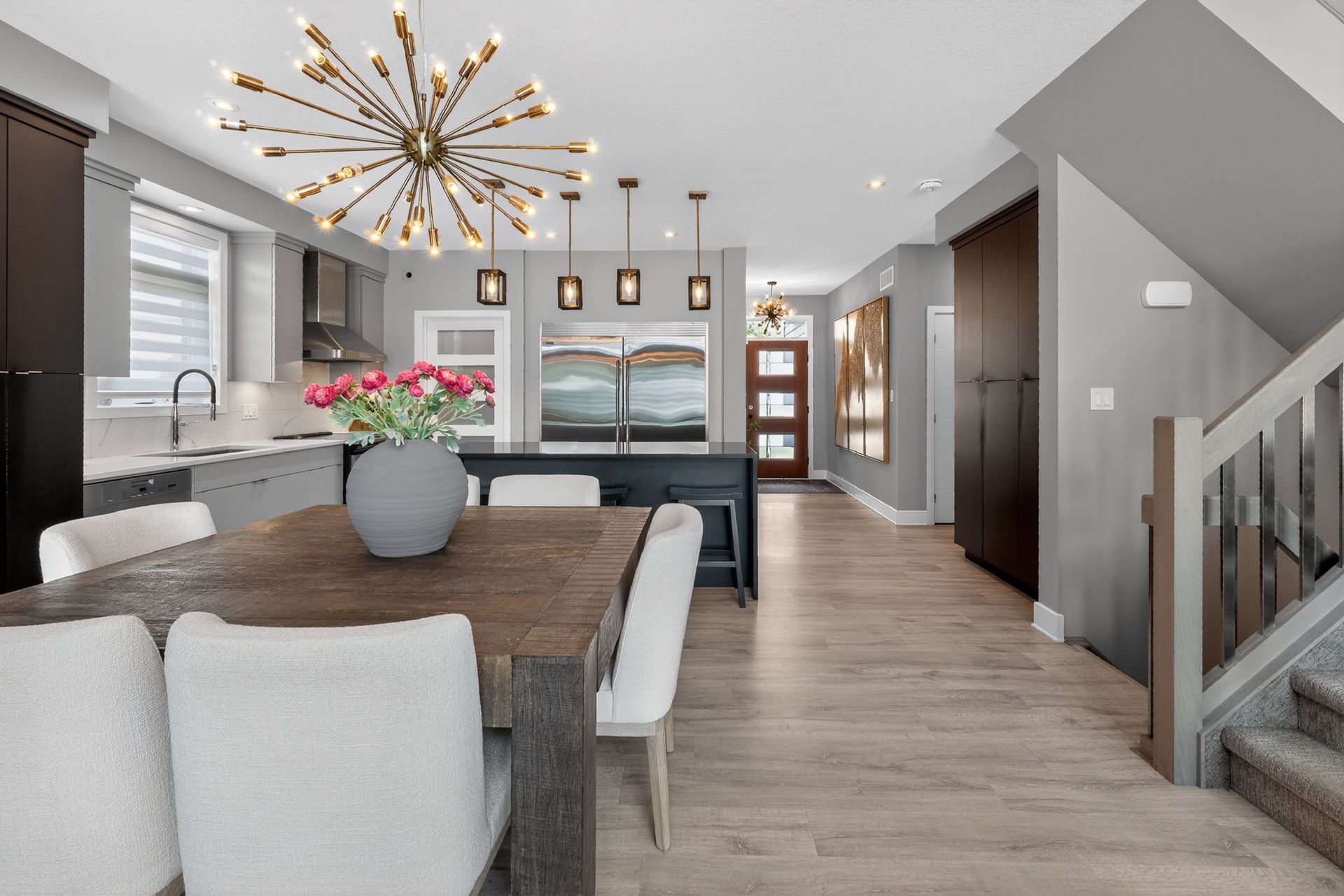 Open-concept dining room and kitchen with sputnik chandelier and wood dining table