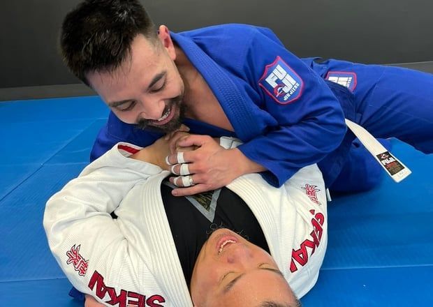 Two men in martial arts uniforms in a grappling position.