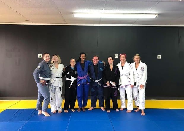 Group of people in martial arts uniforms posing in a gym.
