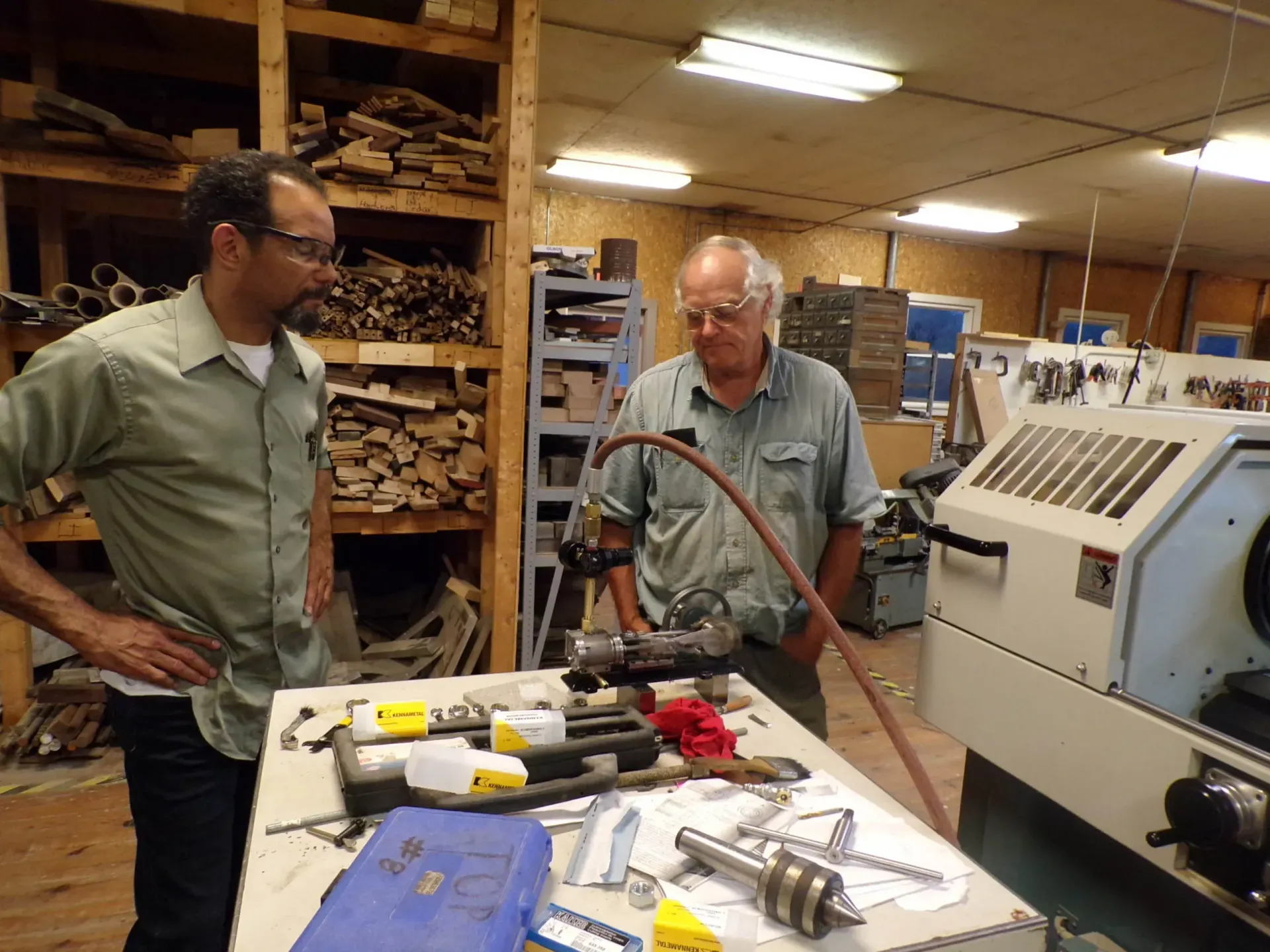 two men are working on a machine in a workshop