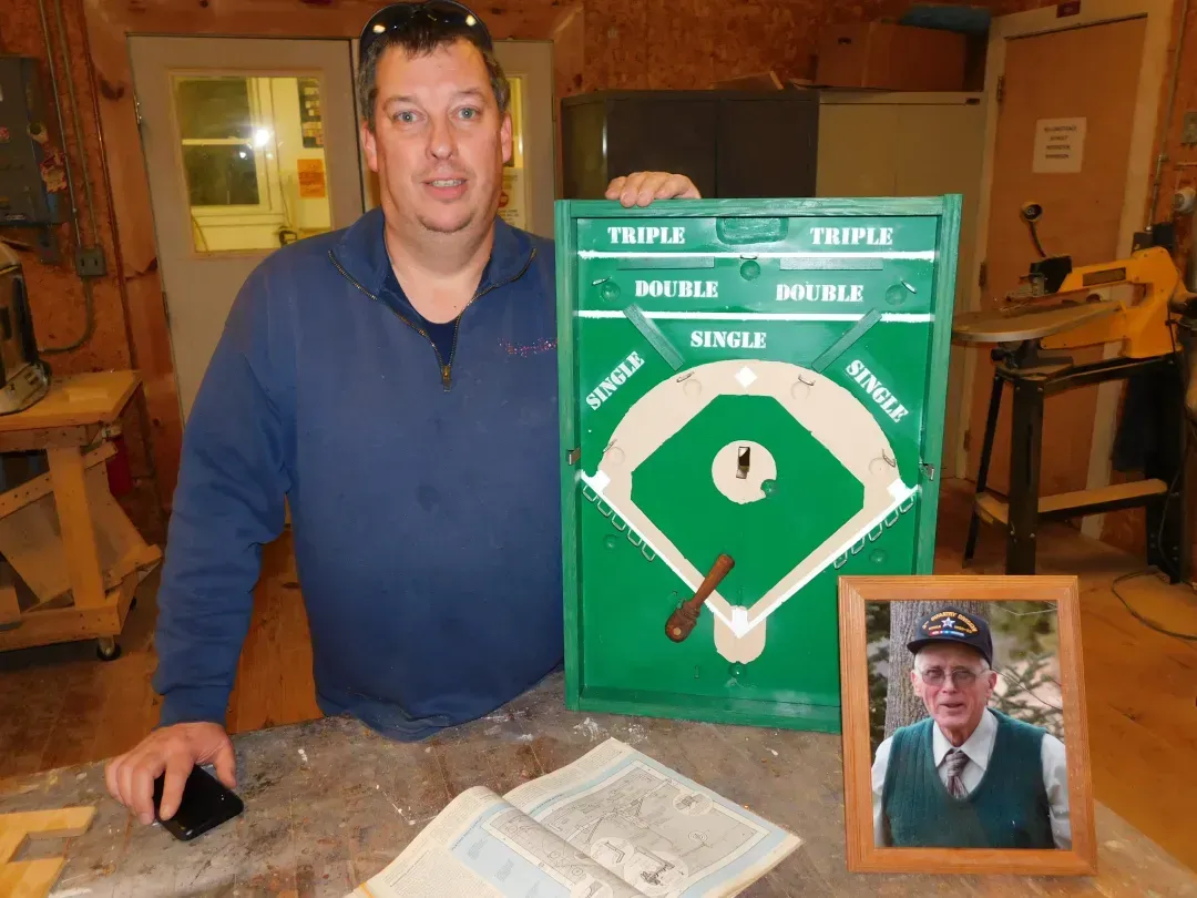 a man in a blue shirt is holding a baseball scoreboard