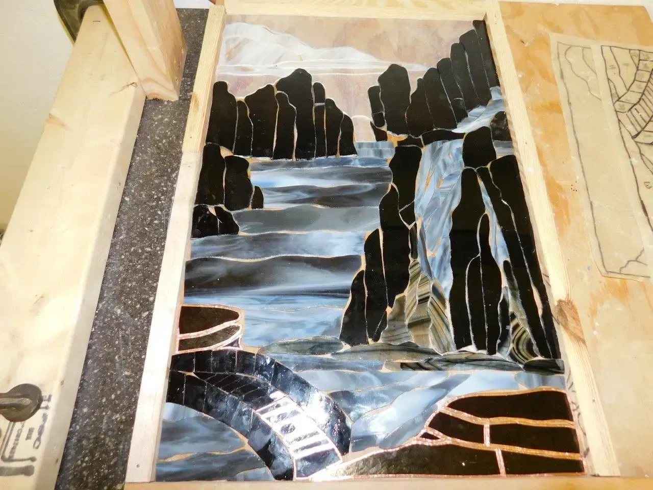 a painting of a waterfall is on a wooden table